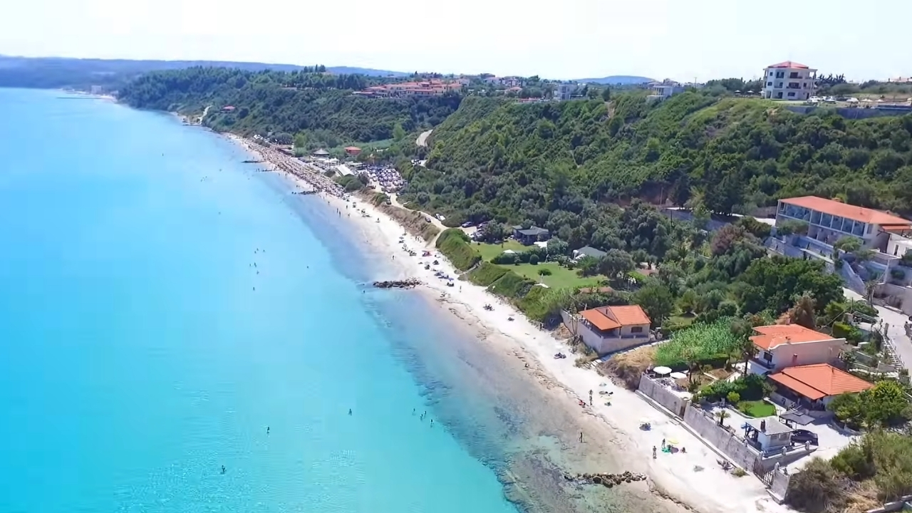 Peščana plaža Afitosa sa tirkiznim morem i zelenim padinama uz obalu