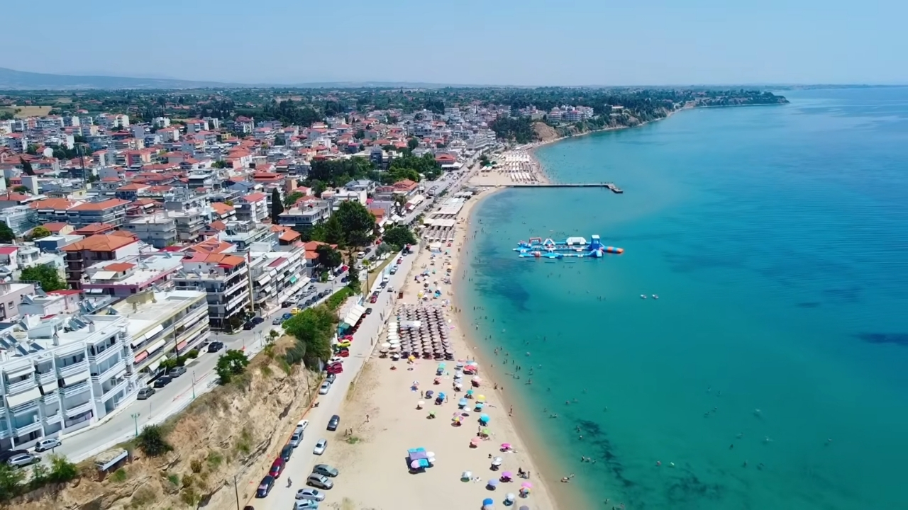 Plaža Nea Kallikratia sa peščanom obalom, tirkiznim morem i gradom uz obalu