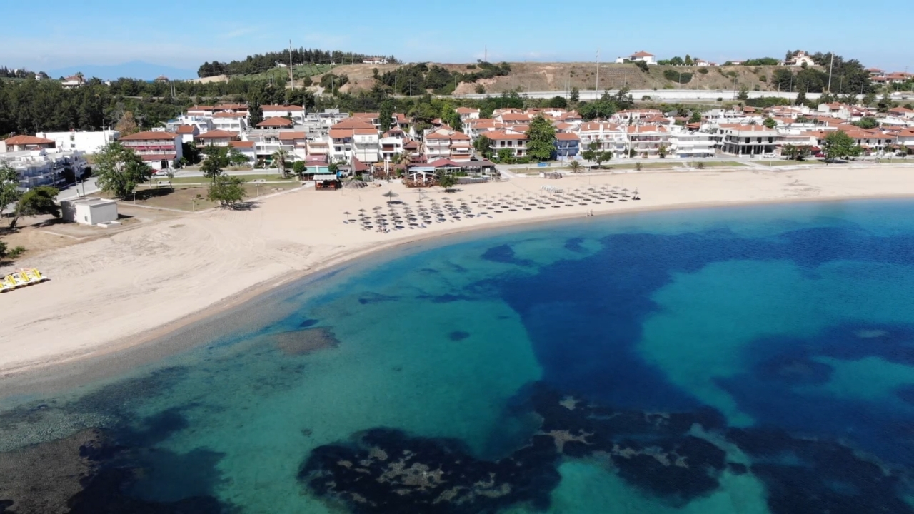 Peščana plaža Nea Potidea sa bistrom tirkiznom vodom i naseljem uz obalu