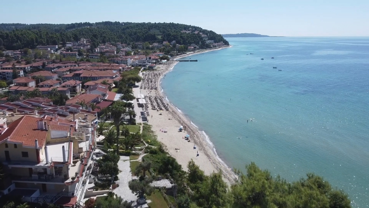 Peščana plaža Siviri sa mirnim morem, ležaljkama i kućama uz obalu